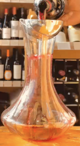 Red wine being decanted into a glass decanter