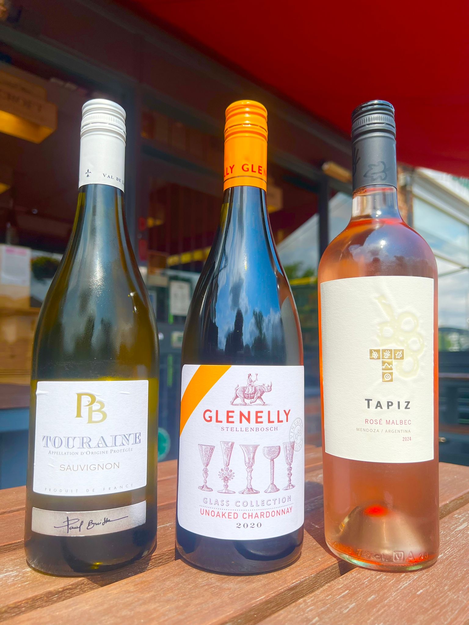 A photograph of three bottles of wine, two whites and a rosé - Touraine Sauvignon Blanc, Glenelly Unoaked Chardonnay, and Tapiz Rosé Malbec - all of which pair well with BBQ food.